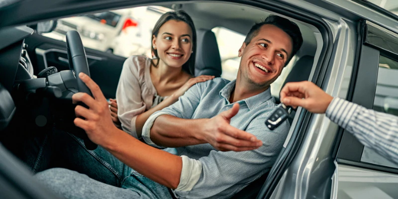 Casal feliz dentro de um carro por assinatura pegando a chave do veículo