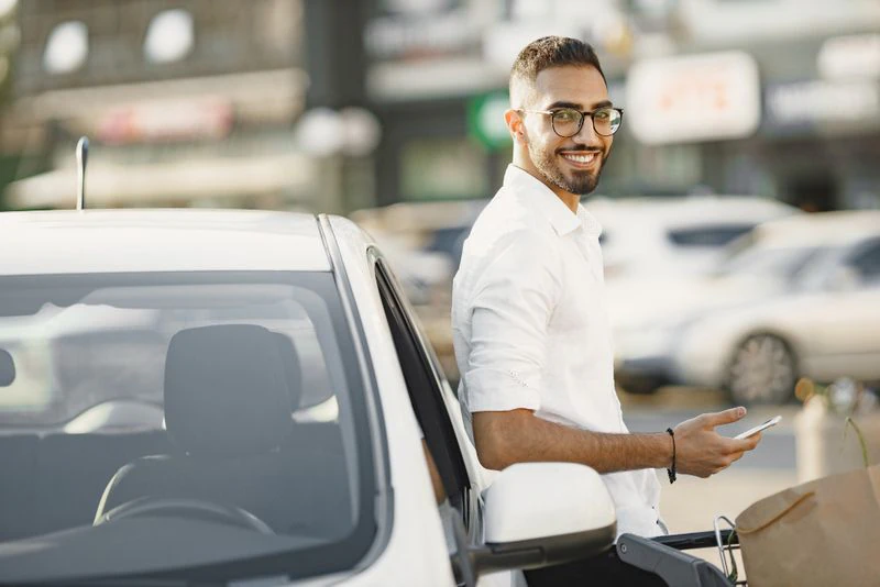 Homem sorrindo ao lado de um carro
