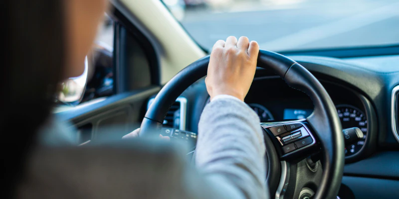 Mulher dirigindo um Carro com Direção Elétrica com destaque para o volante